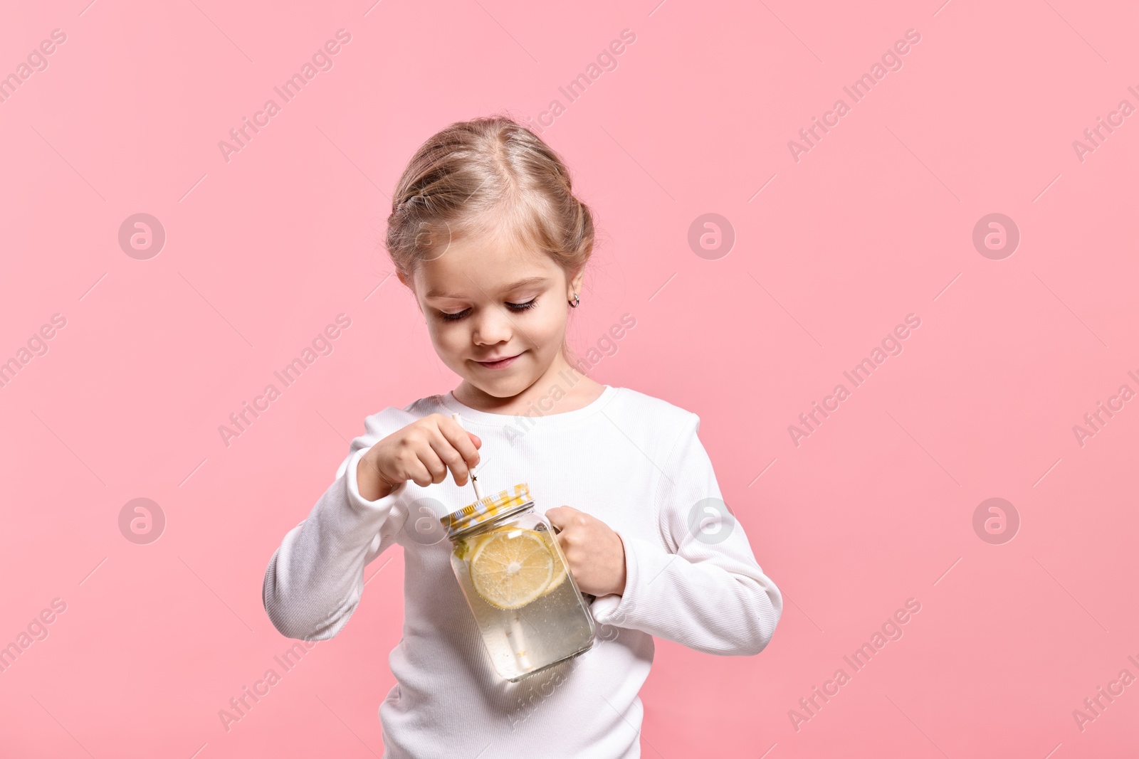 Photo of Girl with mason jar of lemonade on pink background. Refreshing drink