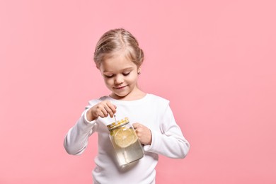 Photo of Girl with mason jar of lemonade on pink background. Refreshing drink