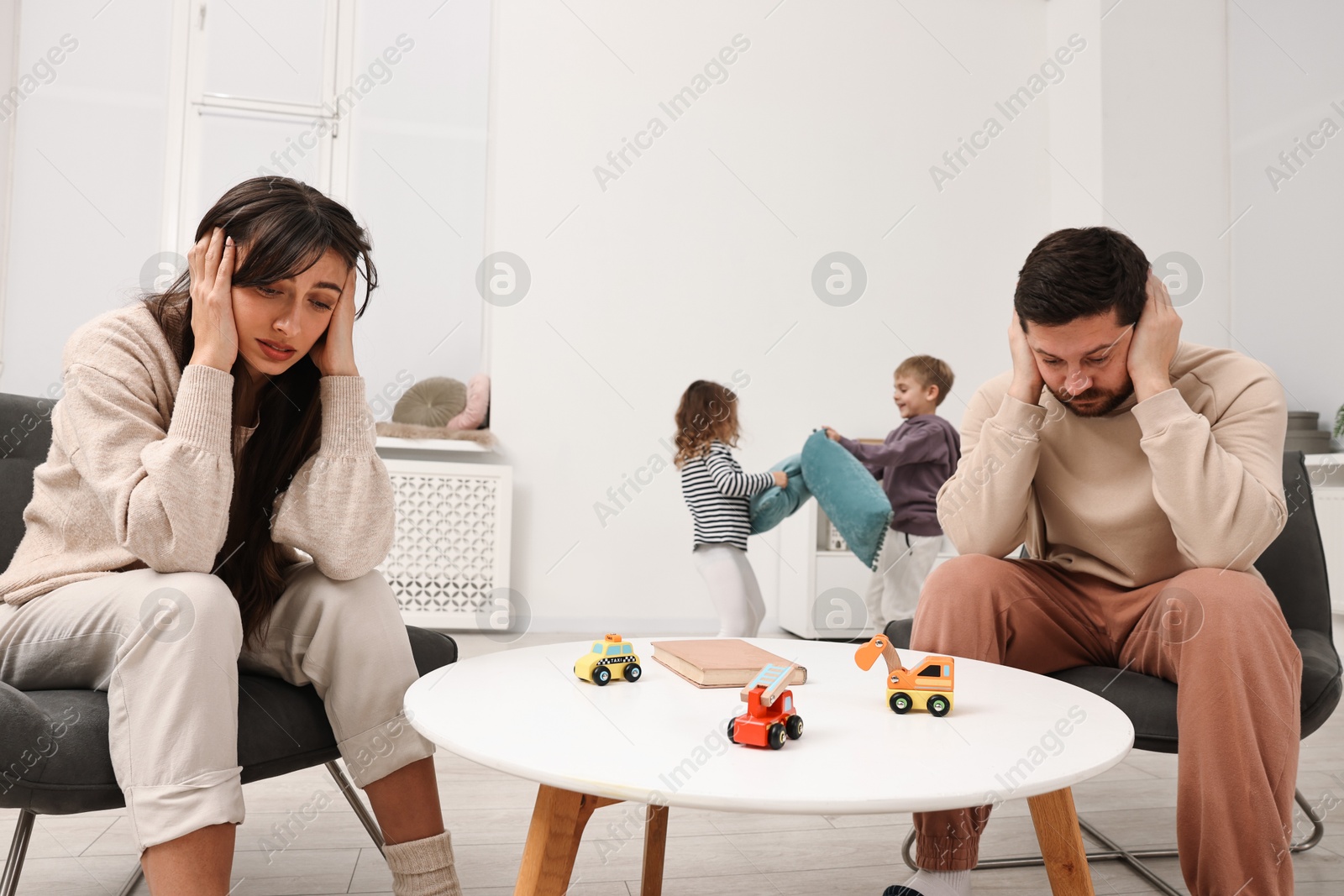 Photo of Overwhelmed parents and their naughty children at home