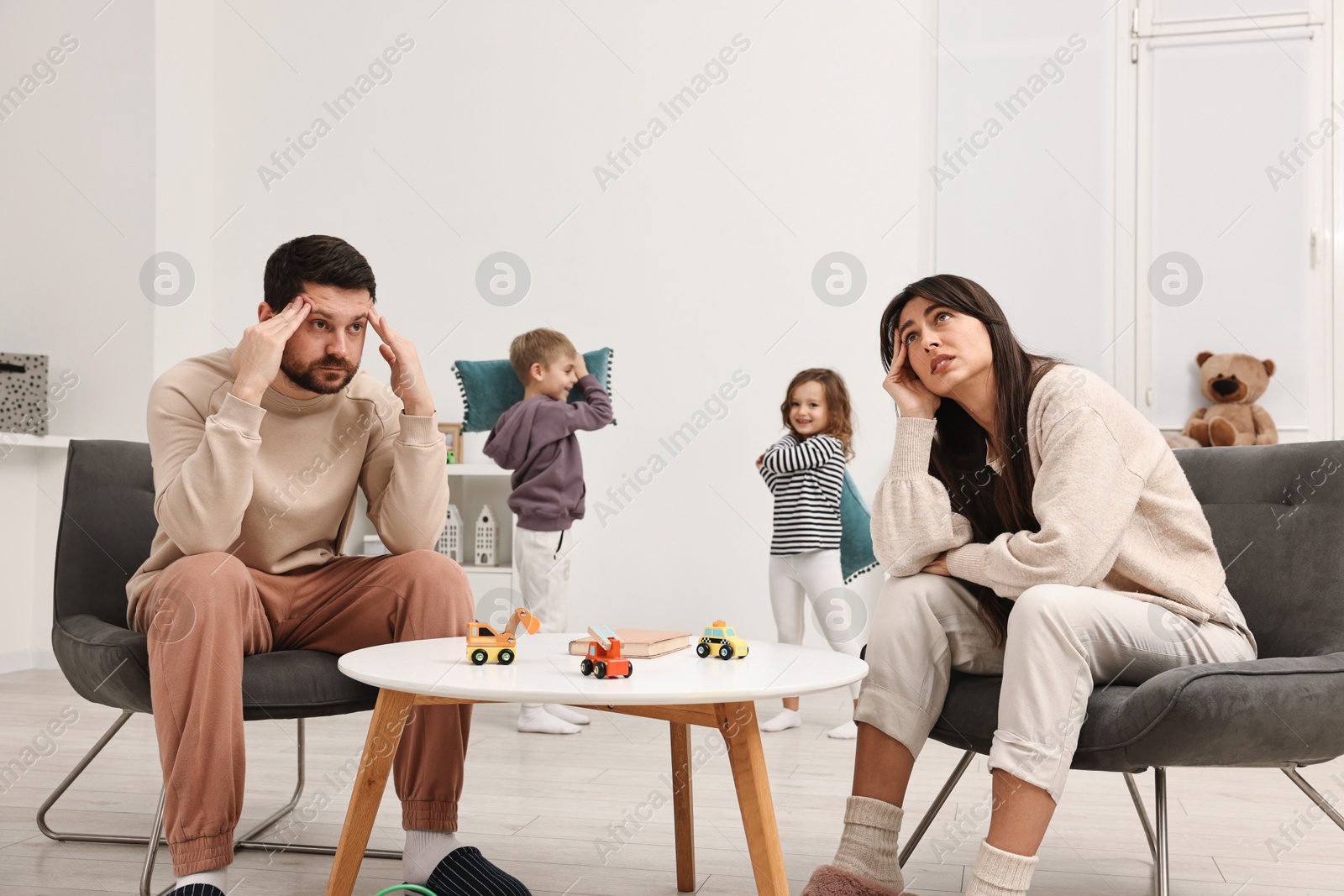 Photo of Overwhelmed parents and their naughty children at home