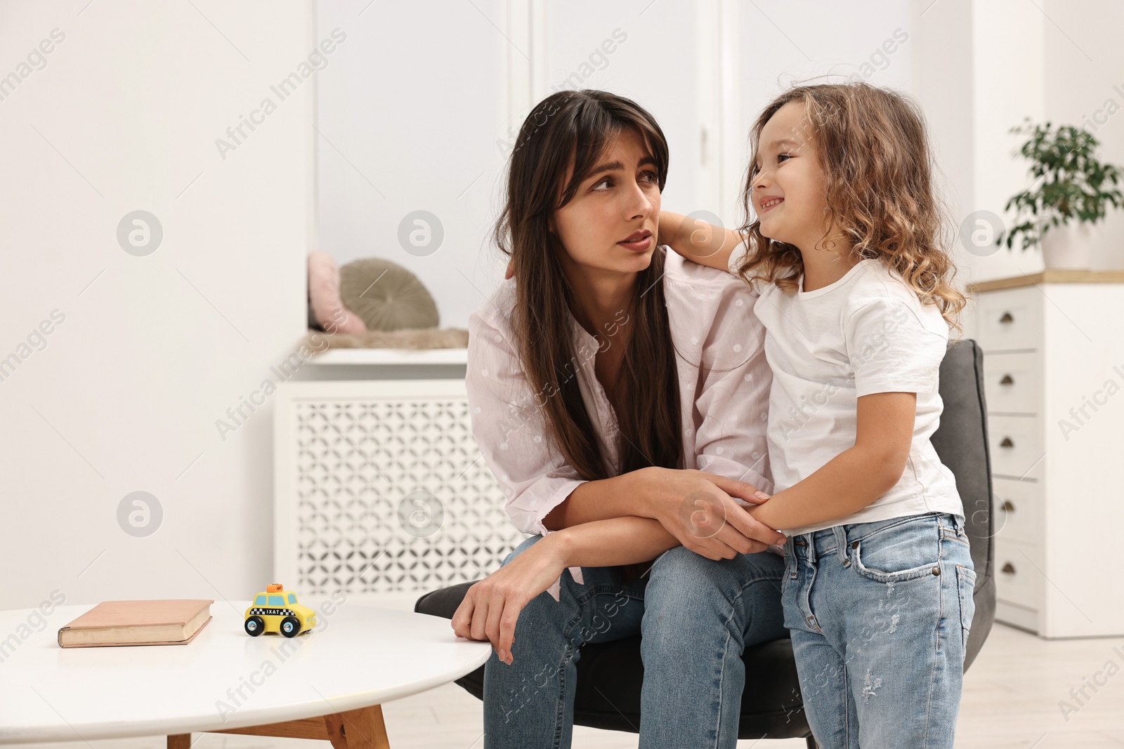 Photo of Overwhelmed mother and her happy daughter at home