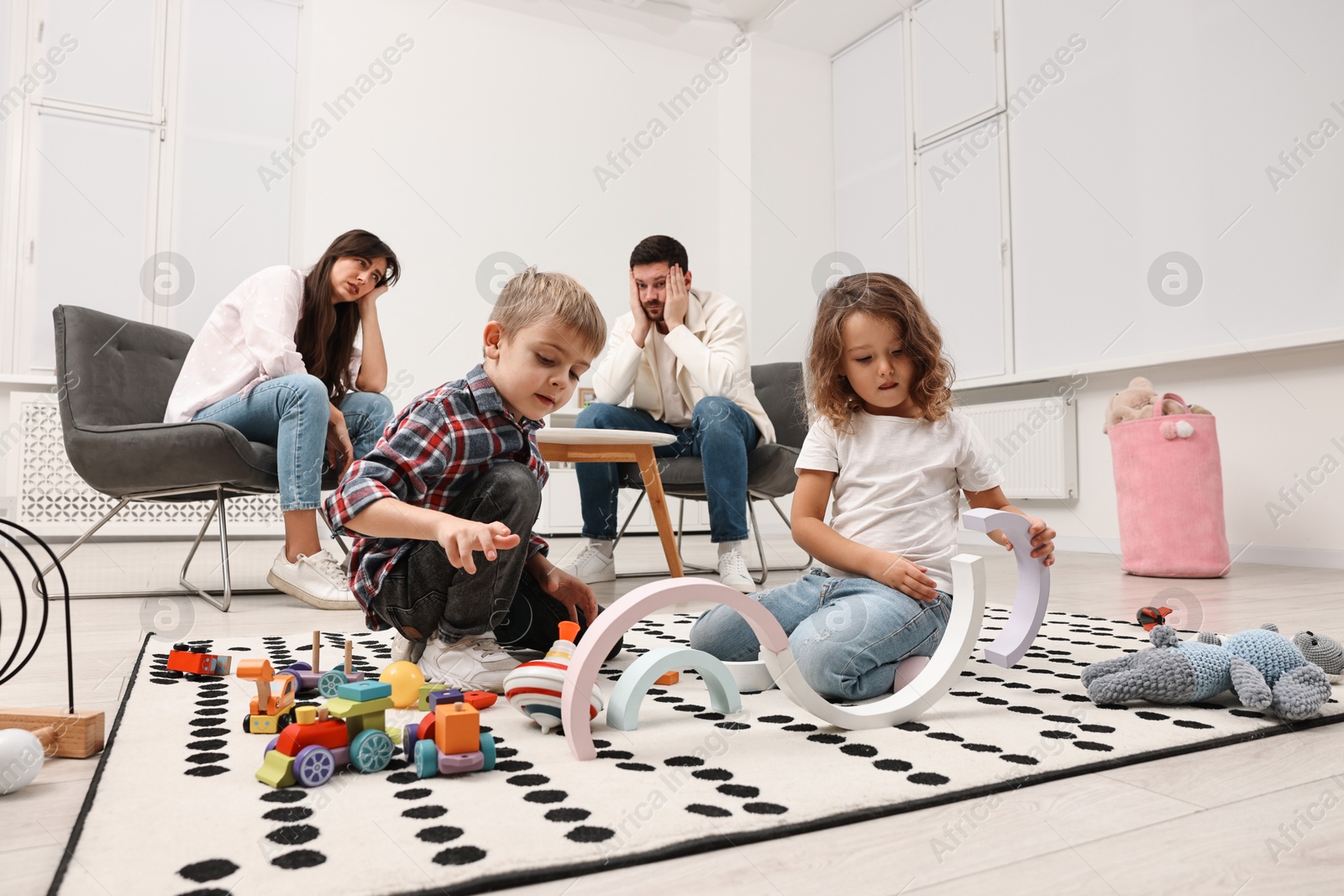 Photo of Hyperactive children playing and their overwhelmed parents at home, low angle view