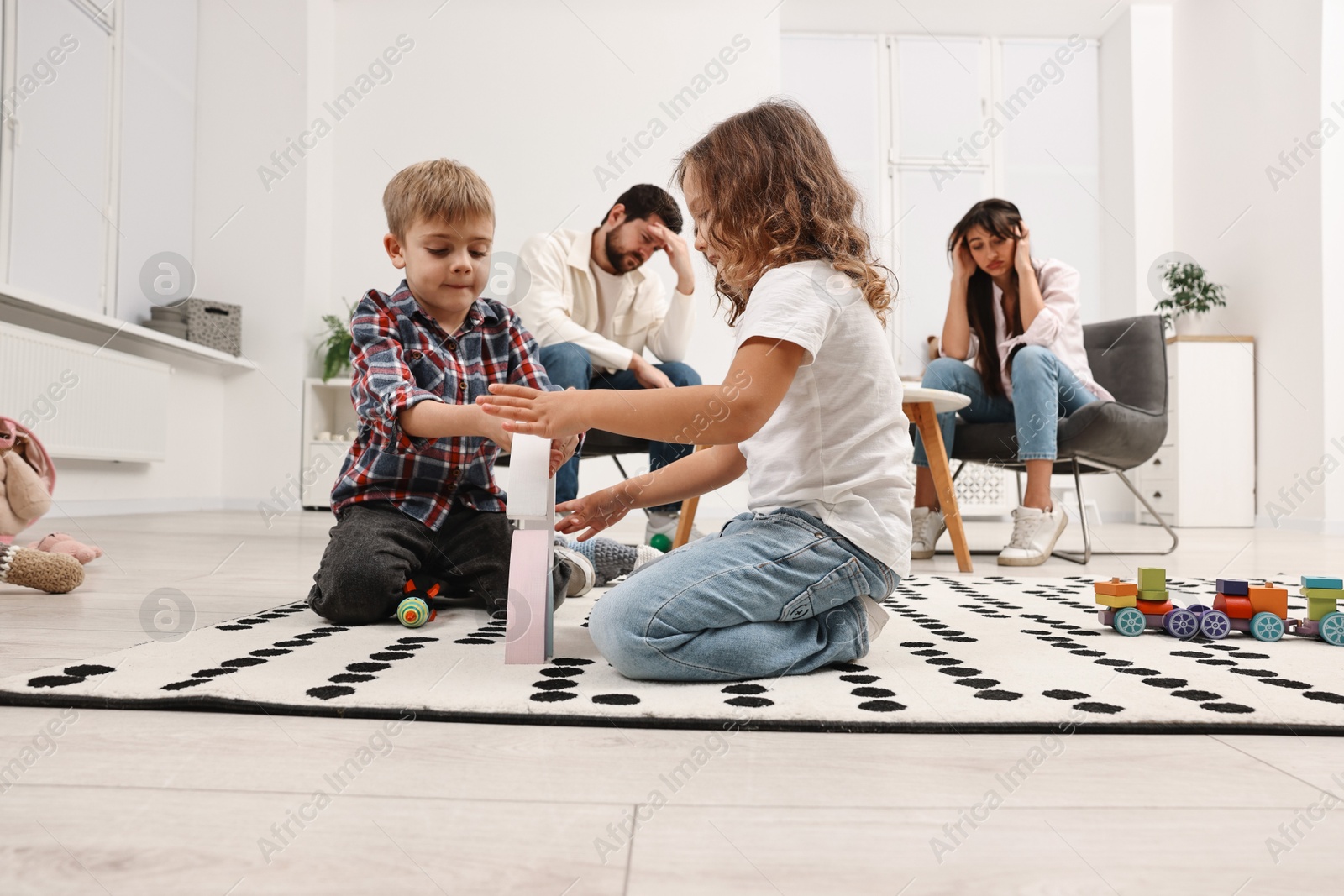 Photo of Hyperactive children playing and their overwhelmed parents at home, low angle view