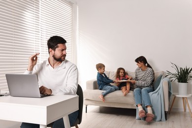 Photo of Noisy children with mother bothering their overwhelmed father at home