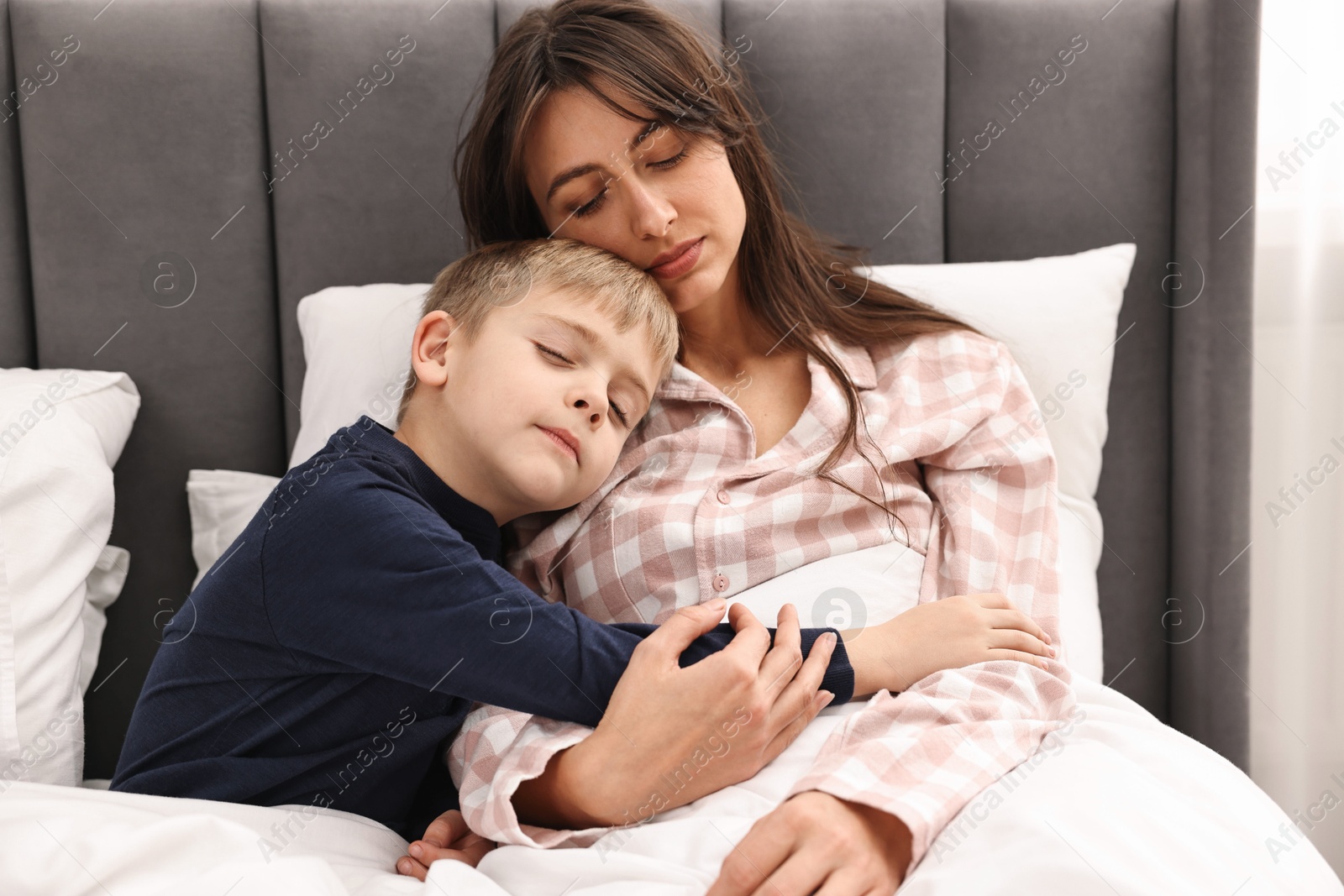 Photo of Overwhelmed mother with her son in bed at home