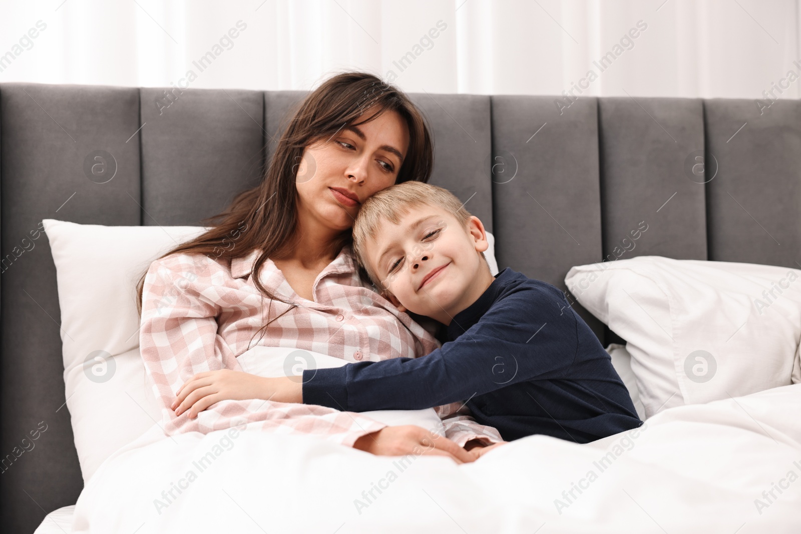 Photo of Overwhelmed mother with her son in bed at home