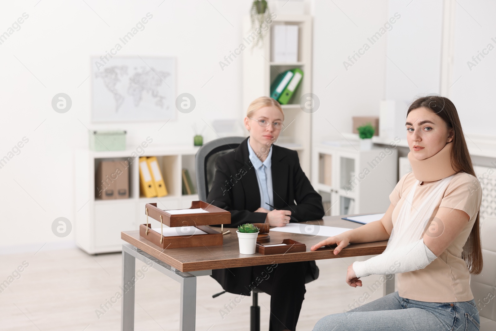 Photo of Injured woman and lawyer at table in office, selective focus