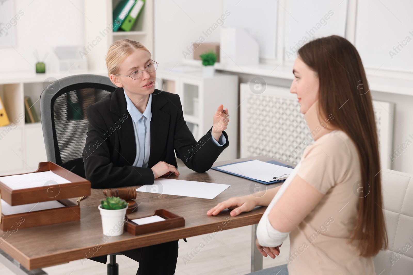 Photo of Injured woman having meeting with lawyer in office, selective focus