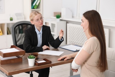 Photo of Injured woman having meeting with lawyer in office, selective focus