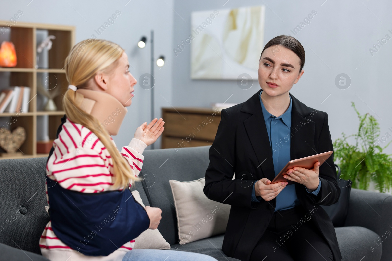 Photo of Injured woman having meeting with lawyer in office, selective focus