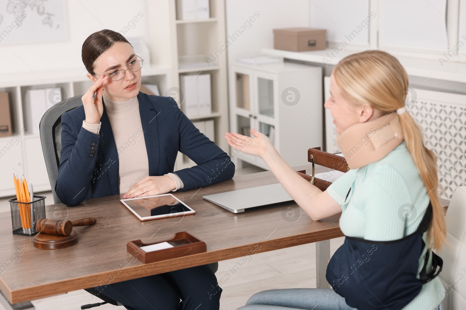 Photo of Injured woman having meeting with lawyer in office, selective focus