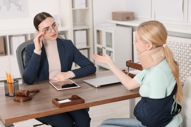 Photo of Injured woman having meeting with lawyer in office, selective focus