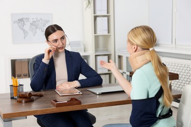 Photo of Injured woman having meeting with lawyer in office, selective focus