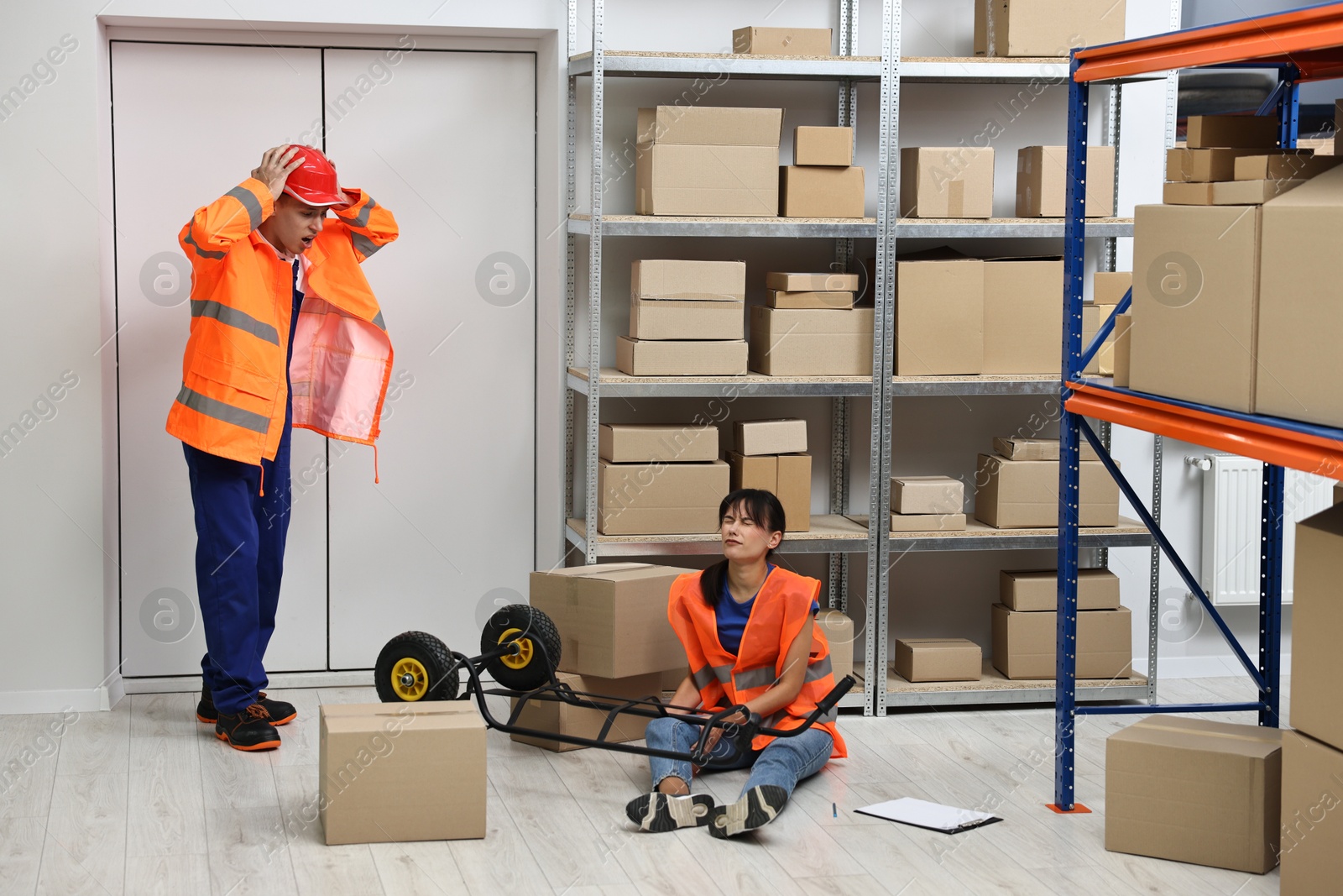 Photo of Accident at work. Worried man and his injured colleague in warehouse