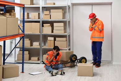 Photo of Accident at work. Worried man and his injured colleague in warehouse