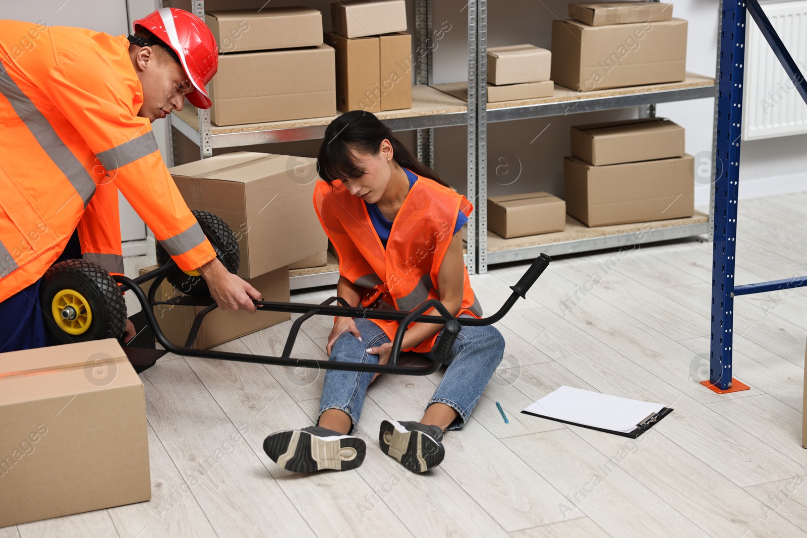 Photo of Accident at work. Man helping his injured colleague in warehouse