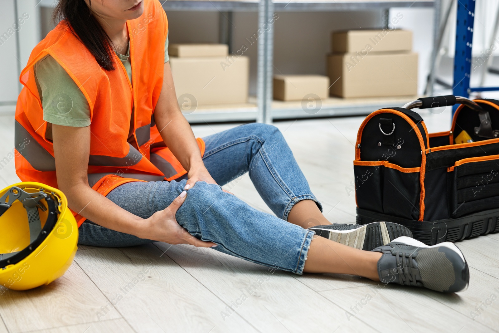 Photo of Accident at work. Woman with injured leg on floor indoors, closeup