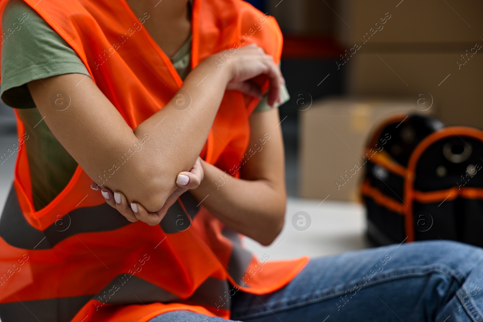 Photo of Accident at work. Woman with injured elbow on floor indoors, closeup