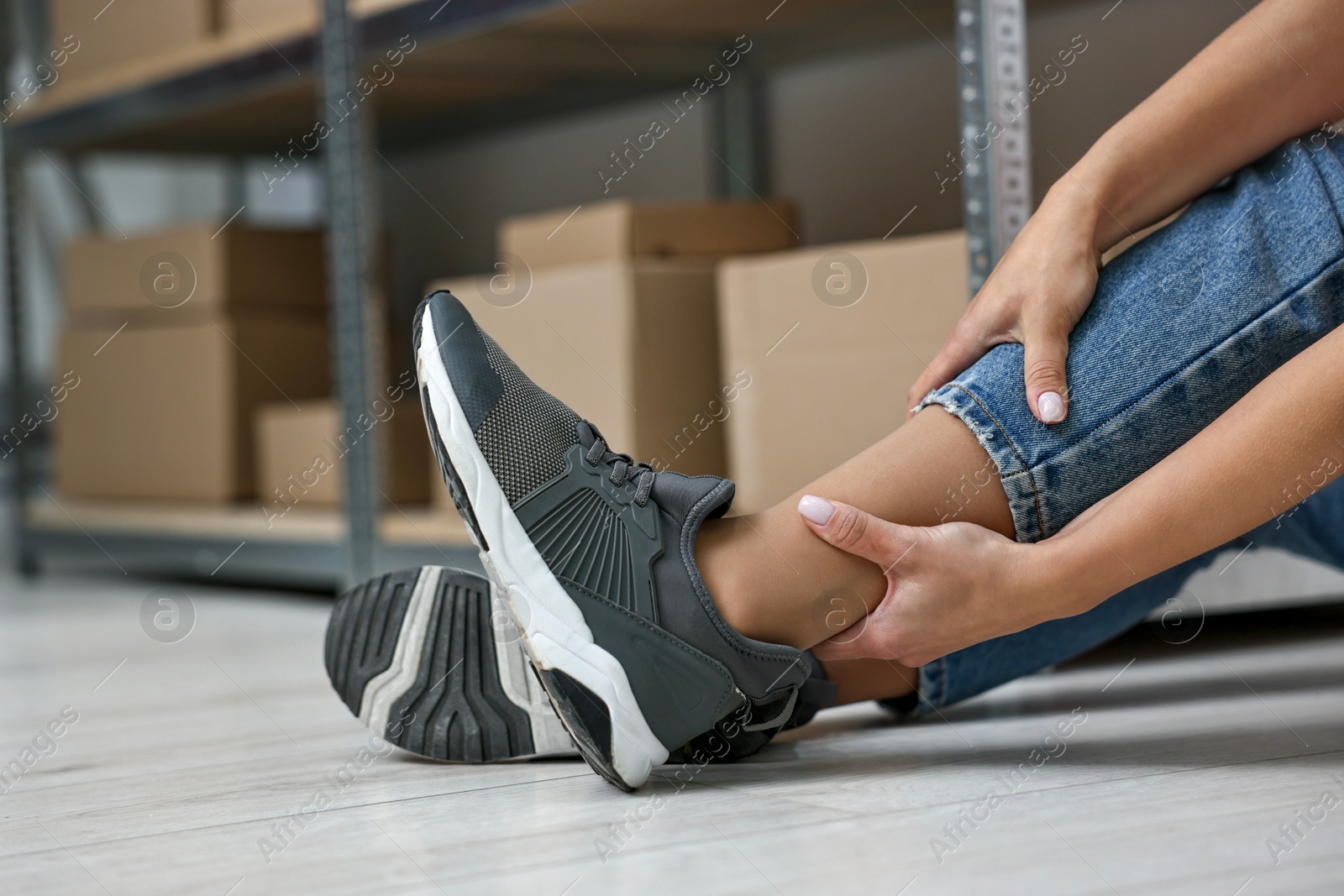 Photo of Accident at work. Woman with injured leg on floor indoors, closeup