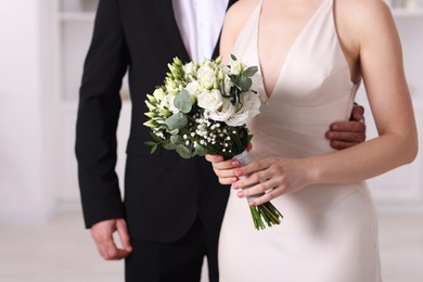 Photo of Bride with beautiful wedding bouquet and groom indoors, closeup