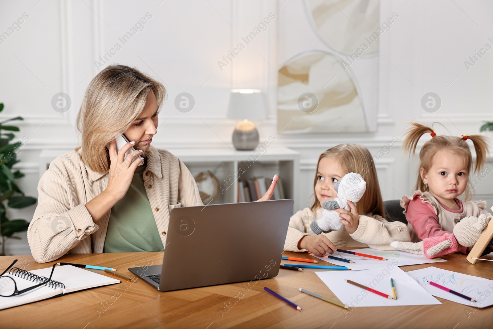 Photo of Work-family balance. Single mother talking by smartphone and refusing to play with her children at wooden table indoors