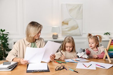 Photo of Single mother working and her children drawing at wooden table indoors