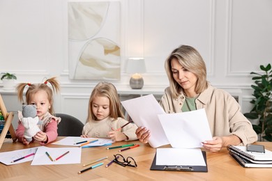 Photo of Single mother working and her children drawing at wooden table indoors