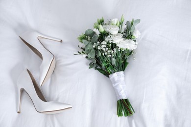 Photo of Wedding bouquet of beautiful flowers and bridal shoes on linens, top view