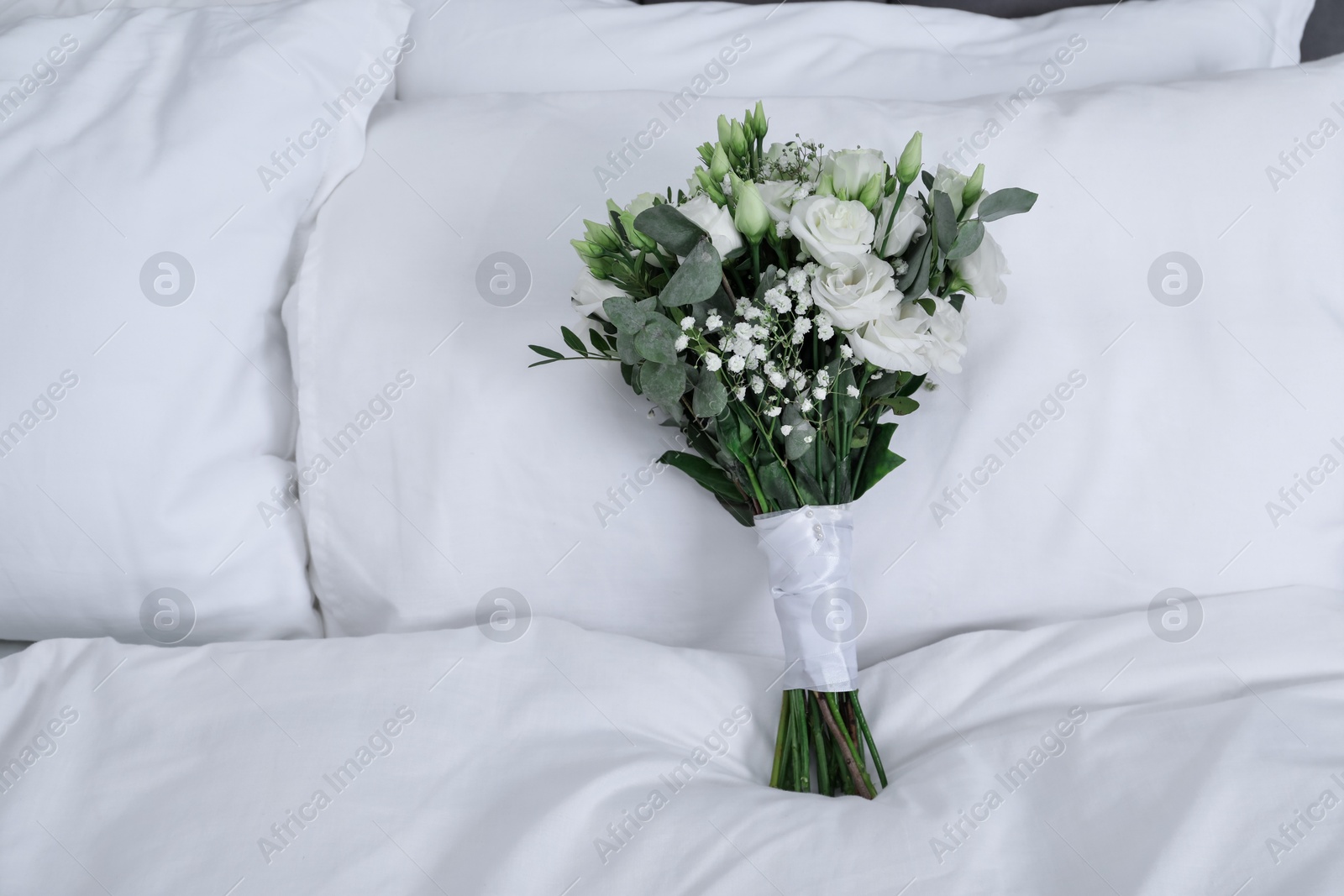 Photo of Wedding bouquet of beautiful flowers and pillows on bed