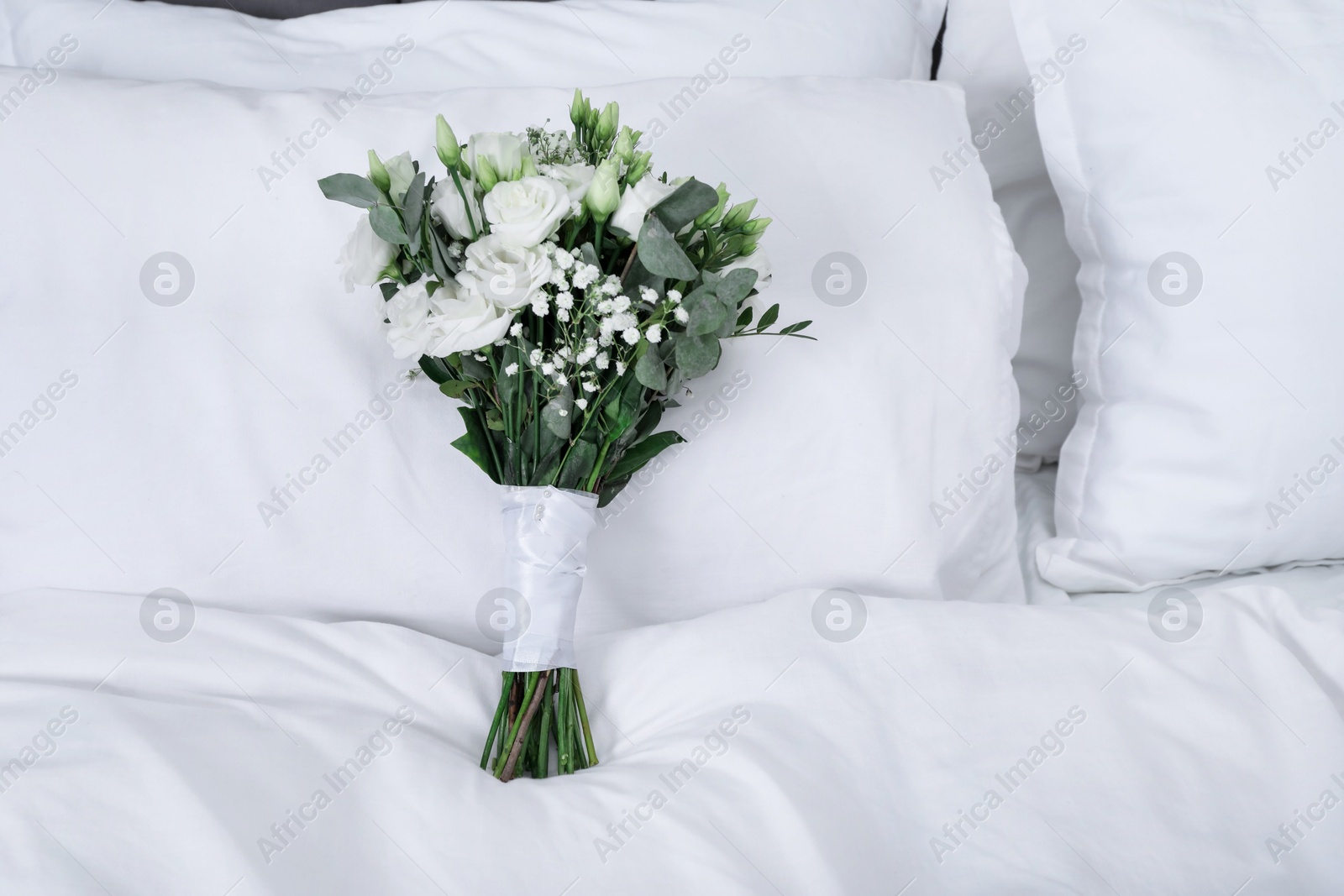 Photo of Wedding bouquet of beautiful flowers and pillows on bed