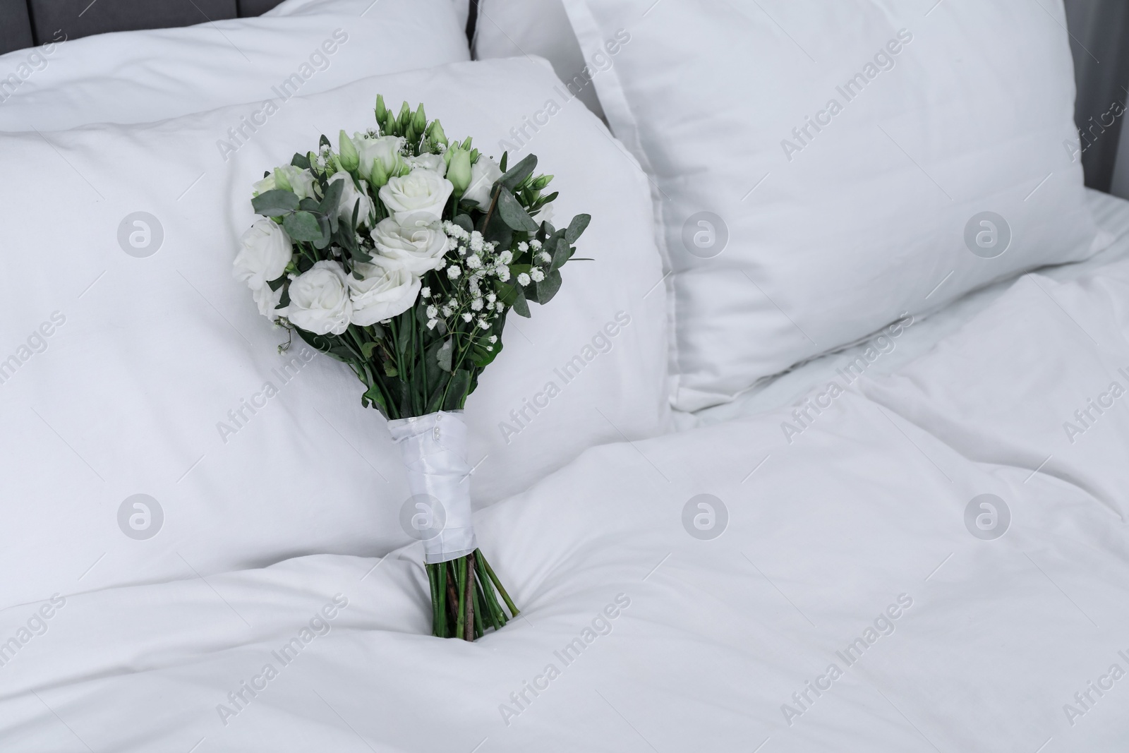 Photo of Wedding bouquet of beautiful flowers and pillows on bed