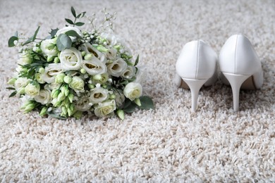 Photo of Wedding bouquet of beautiful flowers and bridal shoes on beige carpet, closeup