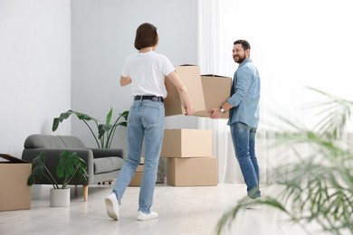 Photo of Moving day. Happy couple with cardboard boxes in their new home