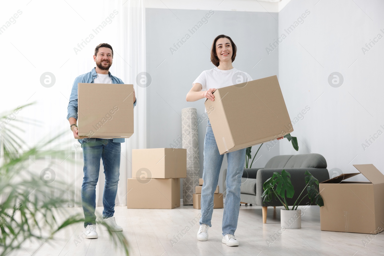 Photo of Moving day. Happy couple with cardboard boxes in their new home