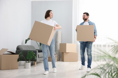 Photo of Moving day. Happy couple with cardboard boxes in their new home