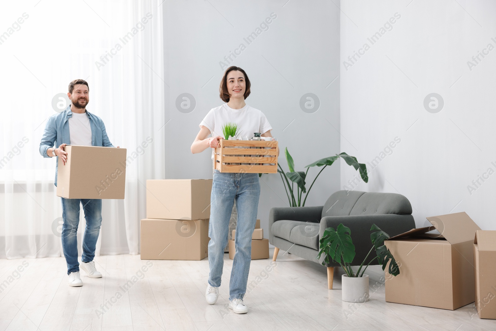 Photo of Moving day. Happy couple with boxes in their new home