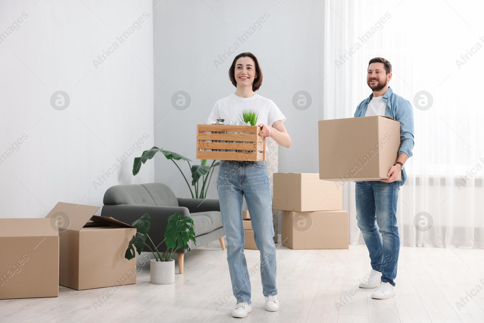 Photo of Moving day. Happy couple with boxes in their new home