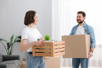 Photo of Moving day. Happy couple with boxes in their new home, selective focus