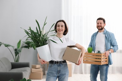 Photo of Moving day. Happy couple with boxes in their new home, selective focus