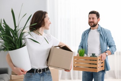 Photo of Moving day. Happy couple with boxes in their new home, selective focus