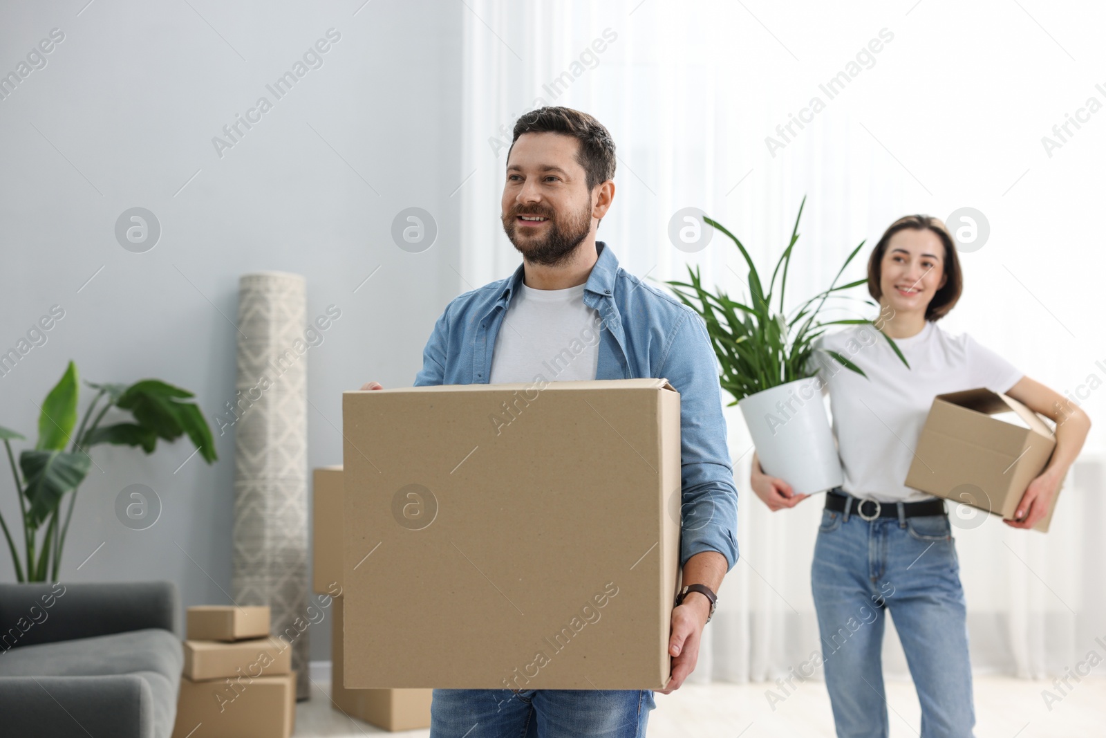 Photo of Moving day. Happy couple with cardboard boxes in their new home, selective focus