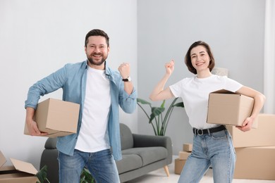 Photo of Moving day. Happy couple with cardboard boxes in their new home