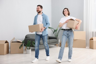 Photo of Moving day. Happy couple with cardboard boxes in their new home