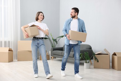 Photo of Moving day. Happy couple with cardboard boxes in their new home