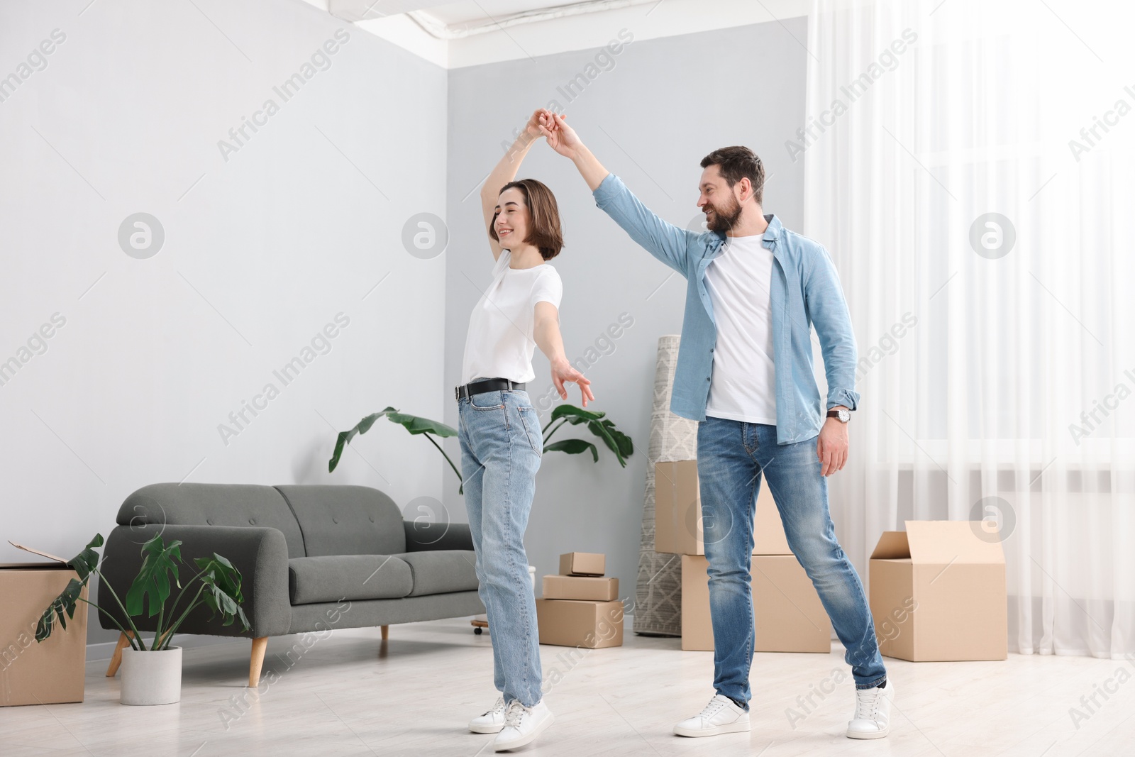 Photo of Moving day. Happy couple dancing in their new home