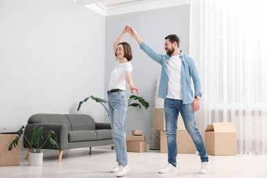 Moving day. Happy couple dancing in their new home