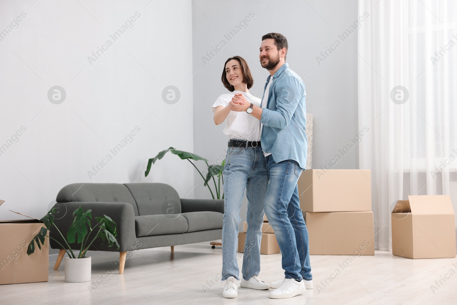 Photo of Moving day. Happy couple dancing in their new home