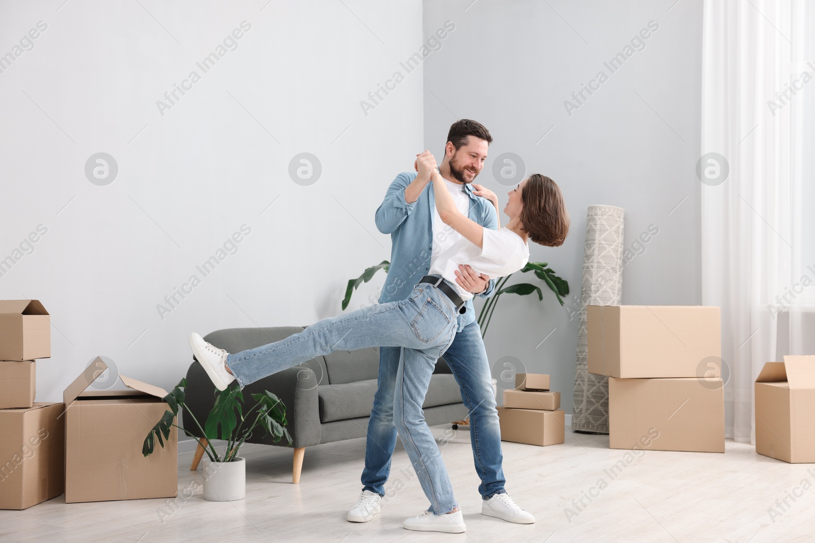 Photo of Moving day. Happy couple dancing in their new home