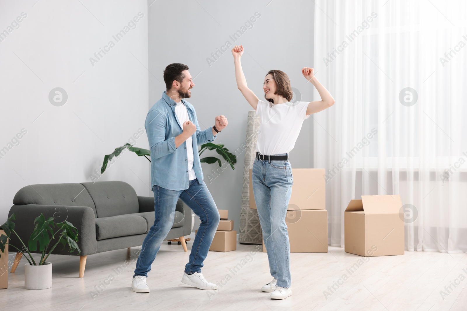 Photo of Moving day. Happy couple dancing in their new home