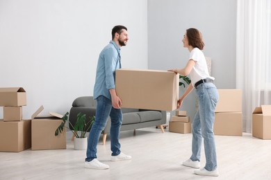 Photo of Moving day. Happy couple carrying box in their new home